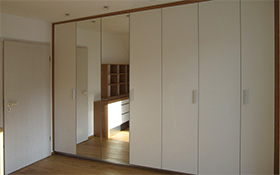 Kleiderschrank mit Faltschiebetüren, Front in weiß mit Spiegel.